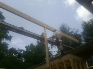 Carpenter setting a ridge beam over a new addition frame — Ice Dam Removal by Roofing Brothers in Hockessin