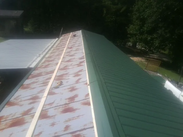 Old rusted panels beside newly installed green metal roofing — Wind Damage Roof Repair by Roofing Brothers in Hockessin