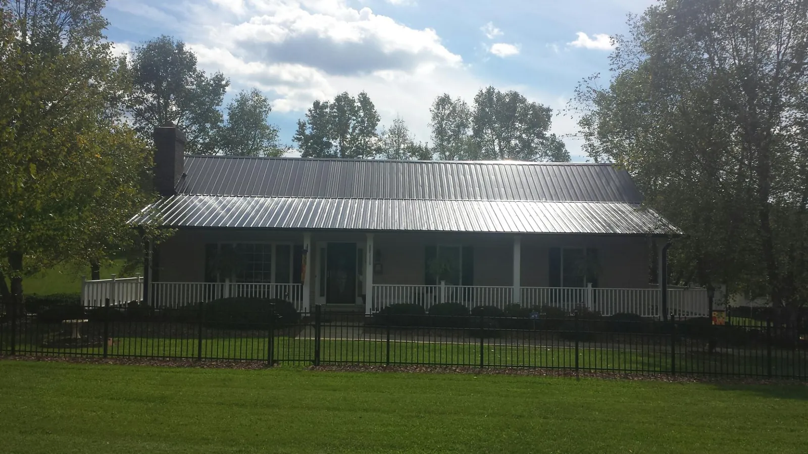 Gray metal roof on a brick ranch with a full width front porch — Gutter Guard Installation work by our crew in Hockessin
